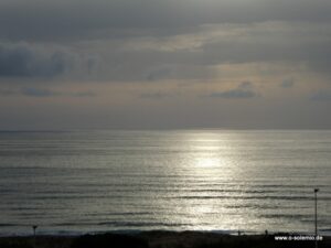 Sonnenlicht spiegelt sich im Meer unter Wolken