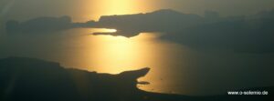 Sonnenuntergang über einer Bucht mit Landzunge