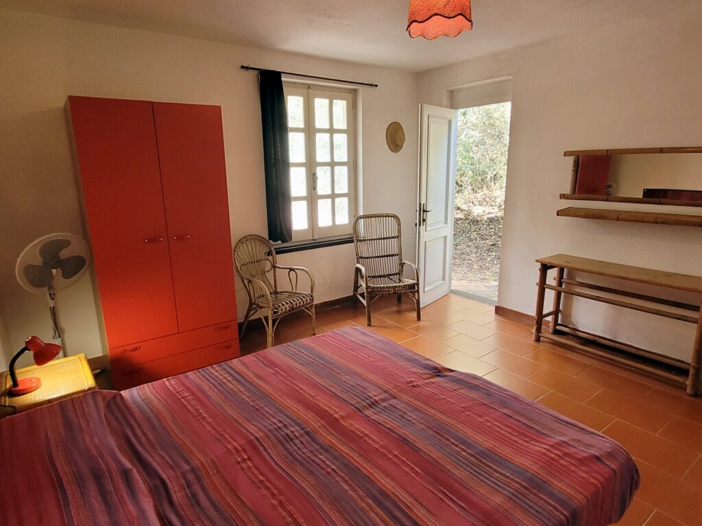 -Villa Magico-023 Villa Domosdei: Schlafzimmer mit rotem Schrank und gestreifter Tagesdecke