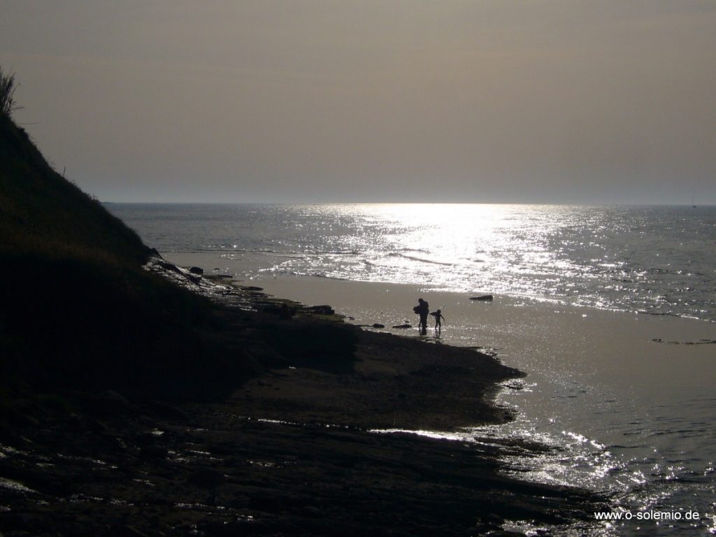 Spaziergänger am Strand im Gegenlicht